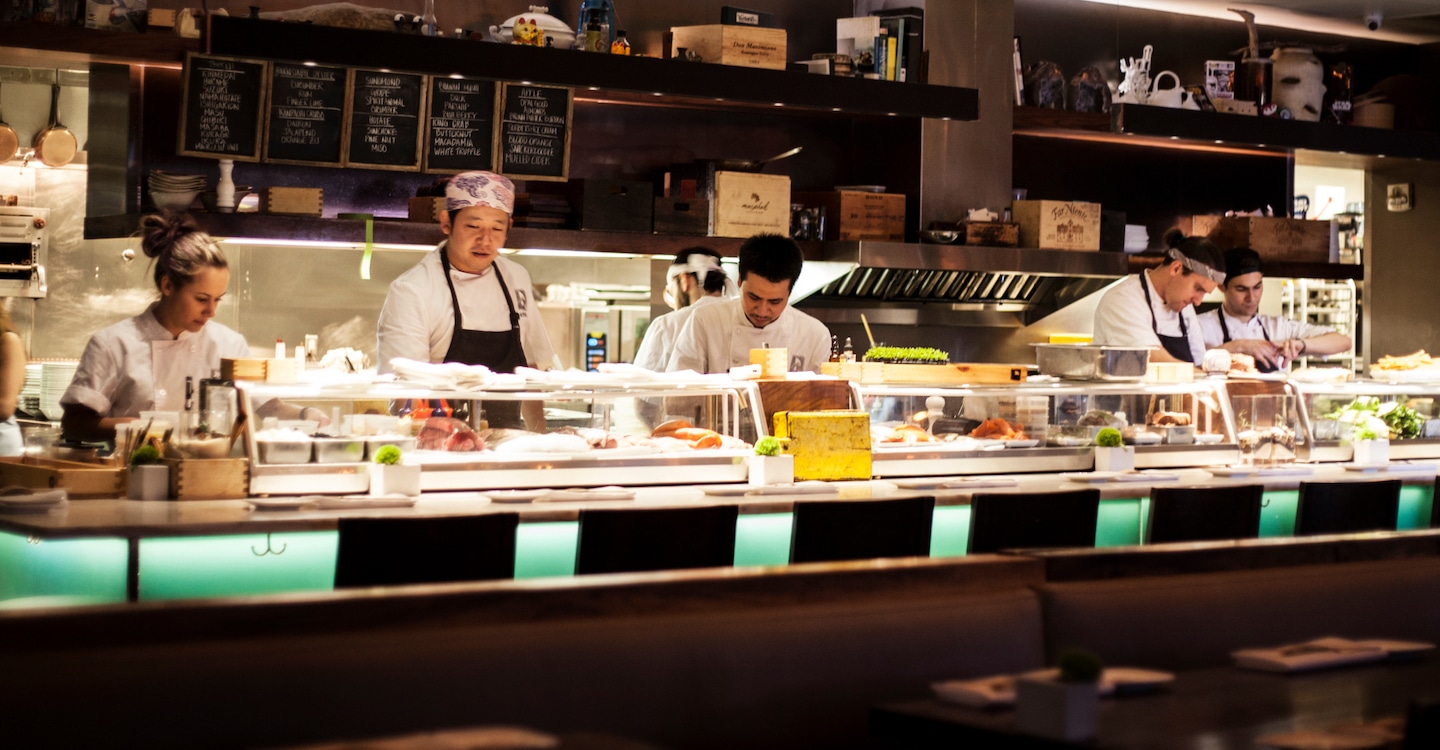 A team of chefs working behind the sushi bar at Uchiko Austin.
