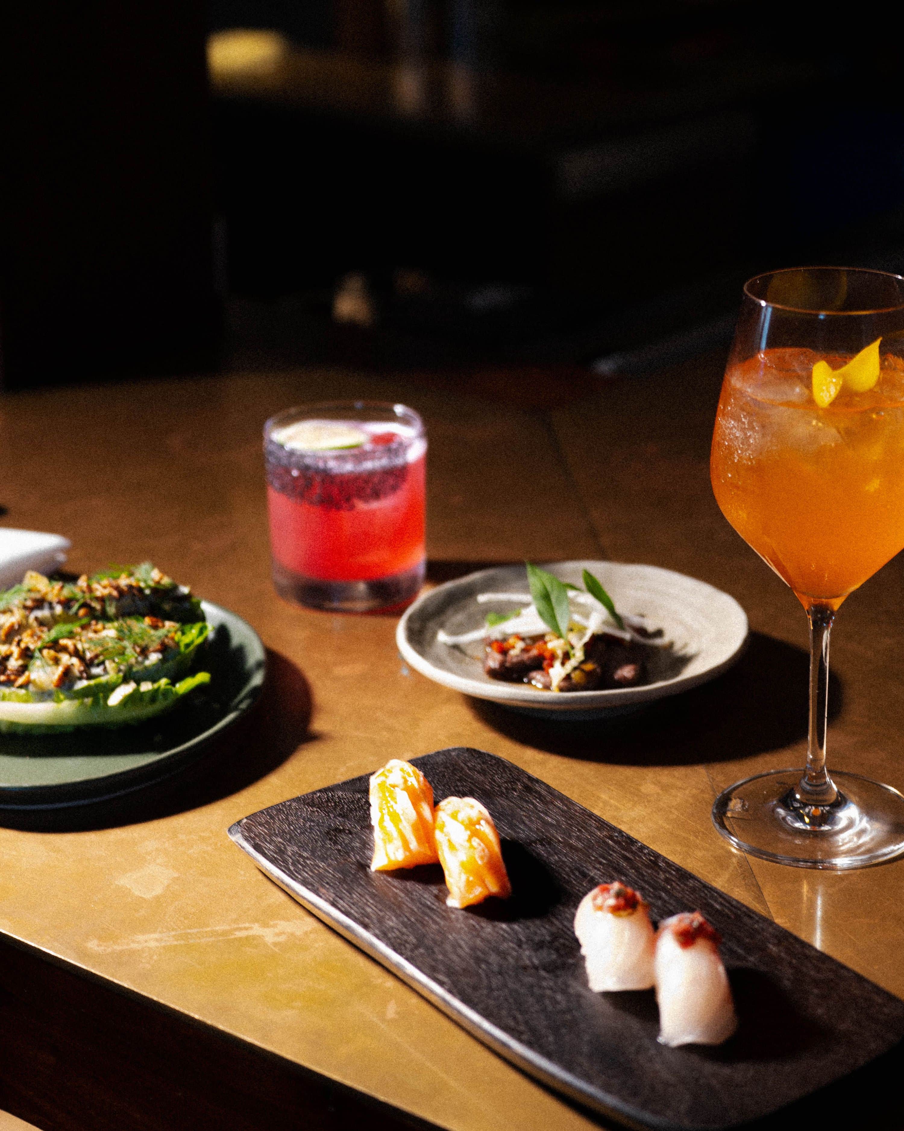 plated nigiri and salad with cocktails for happy hour